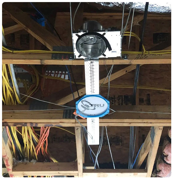 Network infrastructure installation overhead, featuring cabling and a mounted audio system, showcasing technological enhancements for Arch+Vine Apartments in Athens, GA.