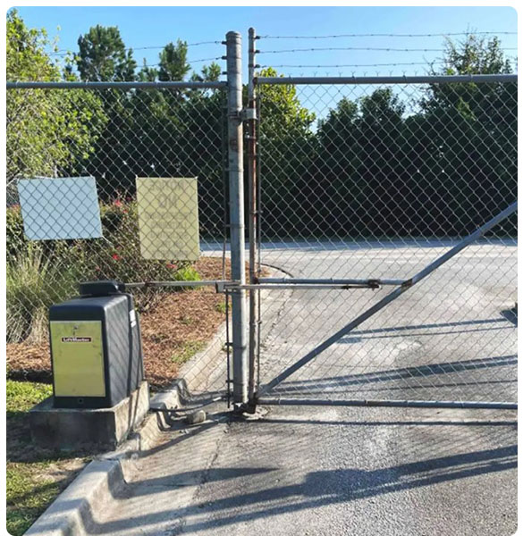 Chain link gate with access control system and signage, surrounded by landscaping, illustrating customized security solutions for properties by SAV Systems.