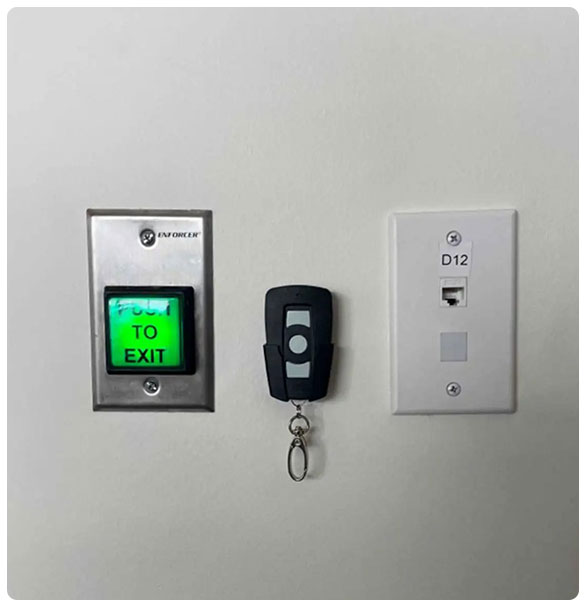 Access control system with green exit button labeled "PUSH TO EXIT," remote key fob, and network port installation, enhancing security for children's indoor play facility.