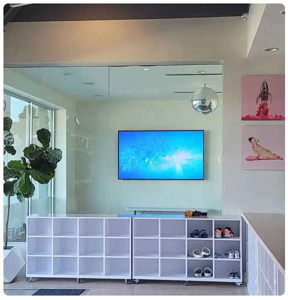 Indoor play facility interior with a large TV displaying an underwater scene, white storage cubbies, a disco ball, and playful wall art, emphasizing a vibrant and engaging environment for children and families.