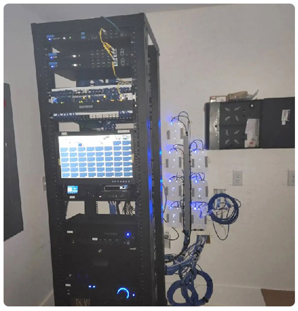 Network equipment rack with servers, switches, and a monitor, showcasing advanced connectivity solutions for commercial audio and video systems at Pointe Grand Apartments.