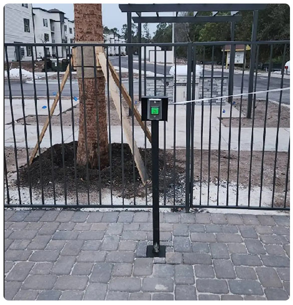 Access control system installation at Pointe Grand Apartments, featuring a secure keypad entry mechanism in front of a gated area under construction.