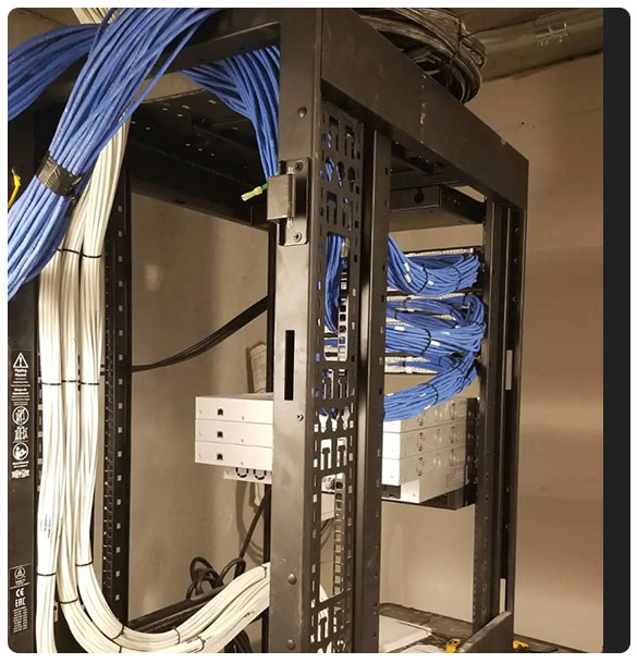 Cabling and network rack installation at Hotel Simone, featuring organized blue and white cables, essential for robust internet coverage and digital infrastructure.