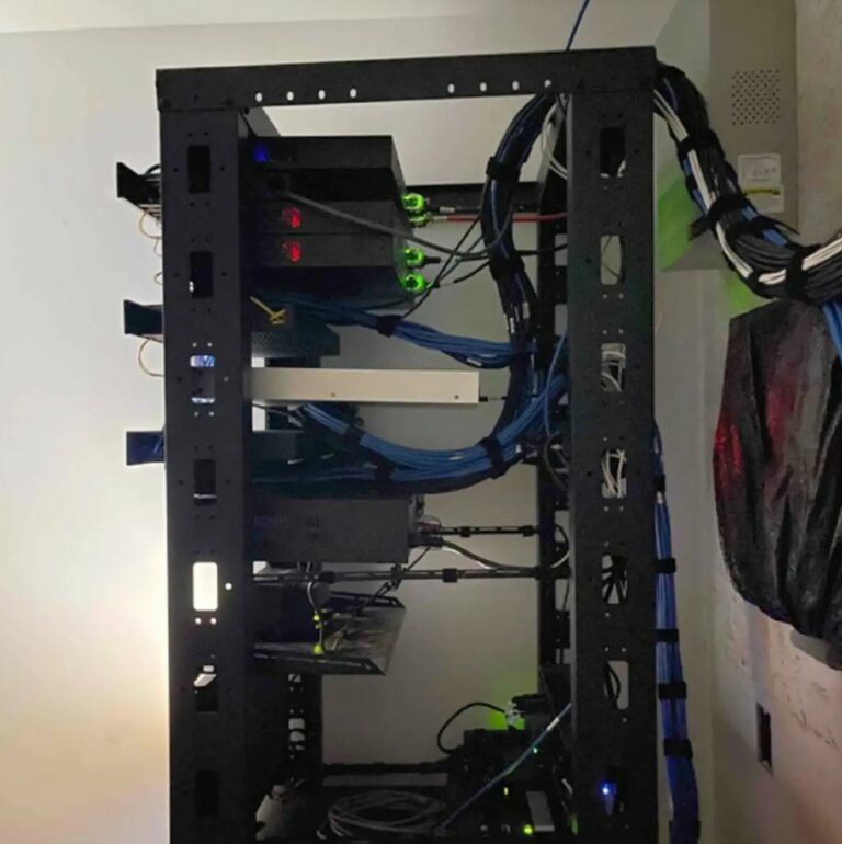 Server rack with network cables and equipment for structured cabling and low-voltage wiring, showcasing infrastructure for surveillance and access control systems in commercial settings.