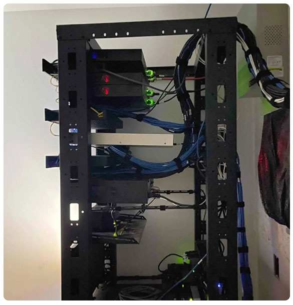 Network equipment rack with multiple servers, switches, and organized blue cables, showcasing advanced wired and wireless network infrastructure for comprehensive connectivity.