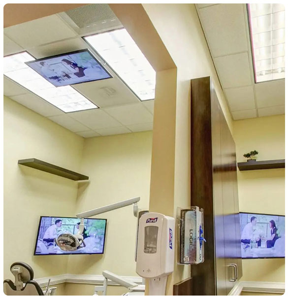 Dental treatment room featuring dual 32" TVs for patient entertainment and consultations, with overhead TV displaying X-rays, enhancing comfort and technology integration at Suwannee Family Dentistry.