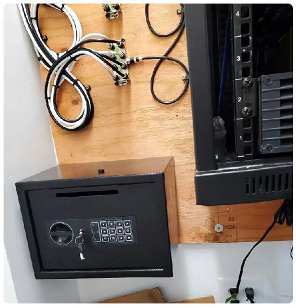Data rack installation with organized cables, security safe with keypad, and wall-mounted infrastructure for McDonough Dental Studio's advanced technology solutions.