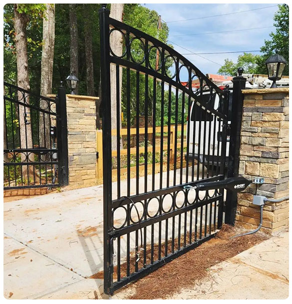 Automatic gate operator installed at a newly constructed residential home in Auburn, GA, showcasing elegant black wrought iron design and stone pillars, enhancing security and convenience for vehicle access.