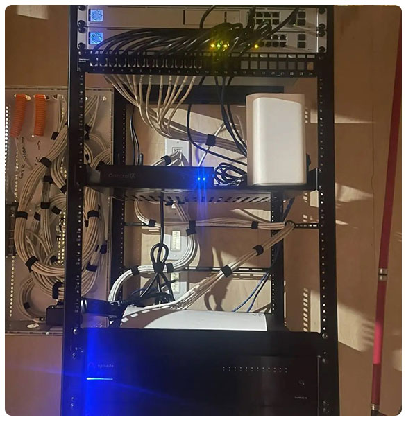 Network equipment rack with organized cabling, featuring Control4 device, router, and network switches, supporting whole-home audio and Wi-Fi installation for a new residential construction in Auburn, GA.