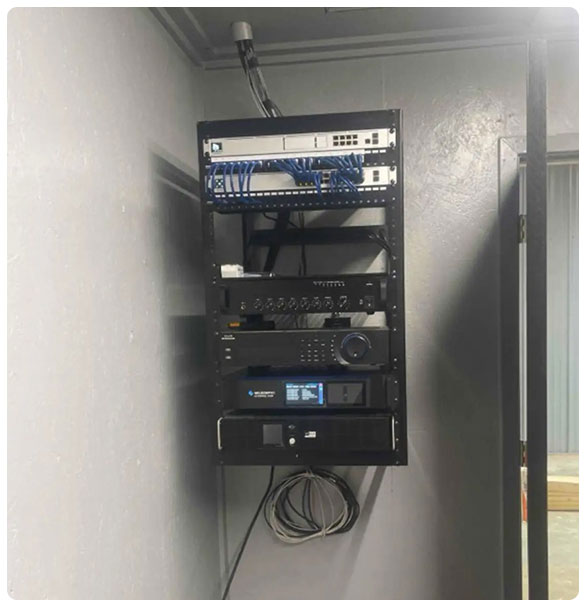 Network equipment rack showcasing audio, video, and networking systems, installed for high-performance motorsport workshop in Madison, GA.