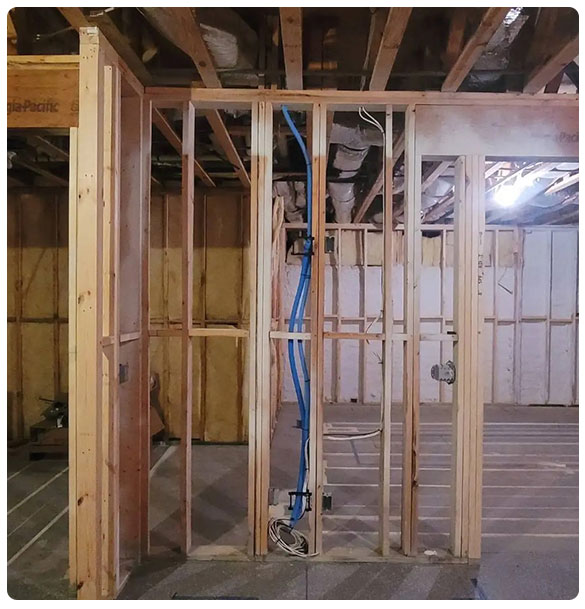 Prewired basement remodel showcasing framed walls with blue networking cables and electrical wiring, setting the foundation for advanced audio, video, and lighting installations in a residential space.