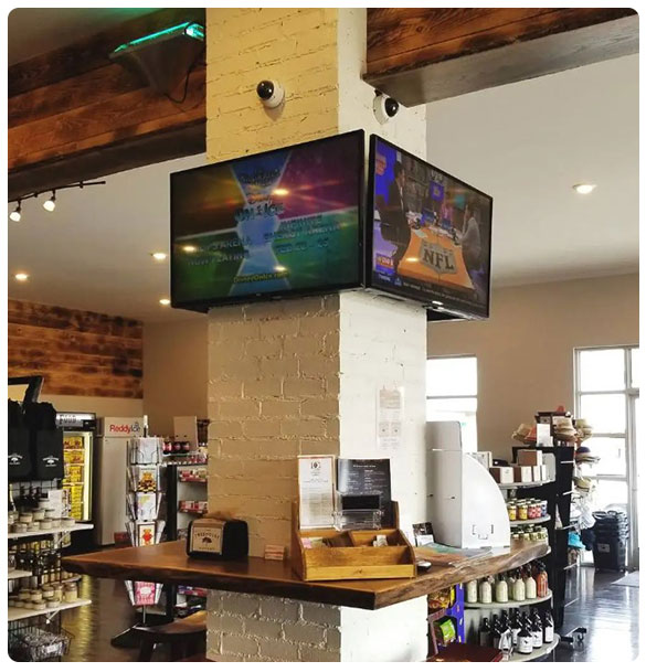 Commercial space featuring security cameras installed near a television displaying NFL content, with a wooden counter and shelves stocked with various products, illustrating a secure and monitored environment for businesses in Atlanta.