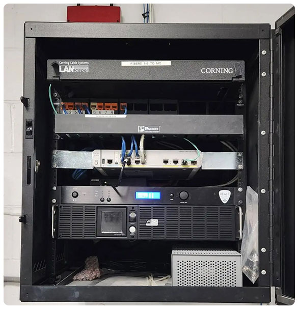 Networking equipment rack featuring Corning LANscape system, Panduit components, and multi-zone audio setup, illustrating comprehensive networking solutions for Standridge Color Corp.